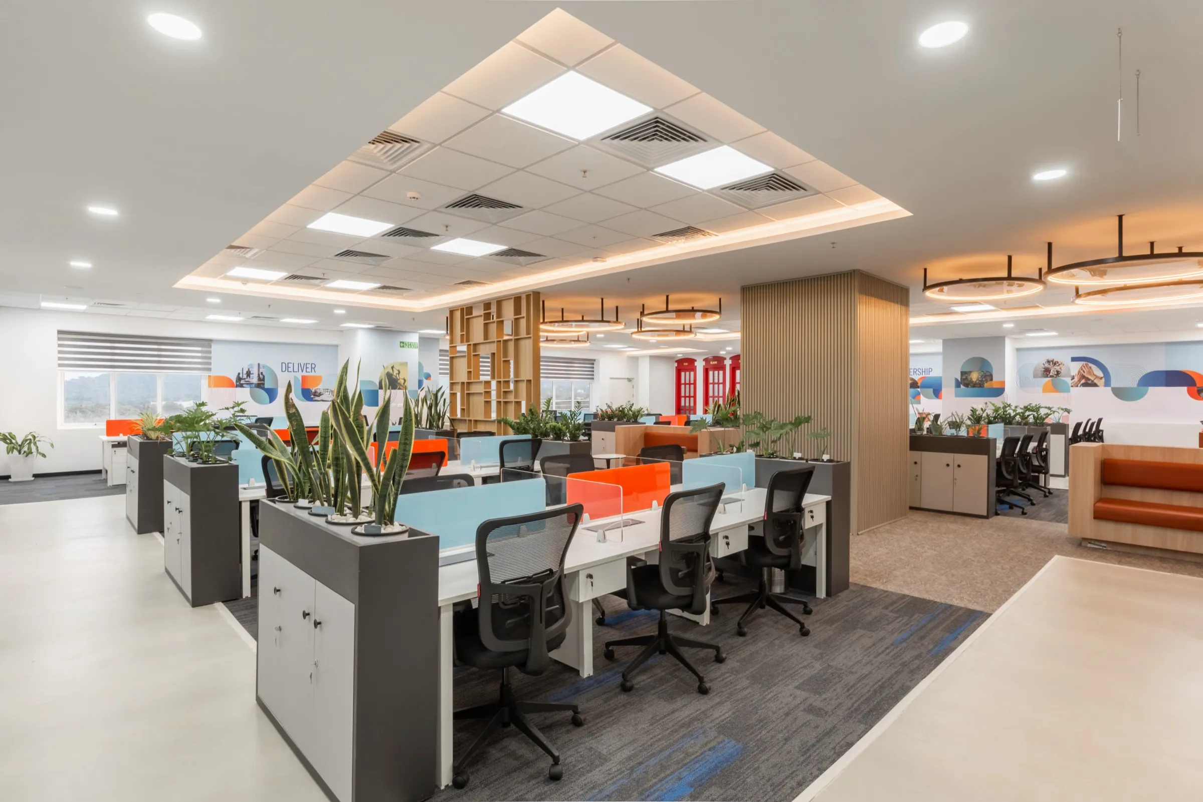 Rows of workstations separated by planter boxes under a coffered ceiling